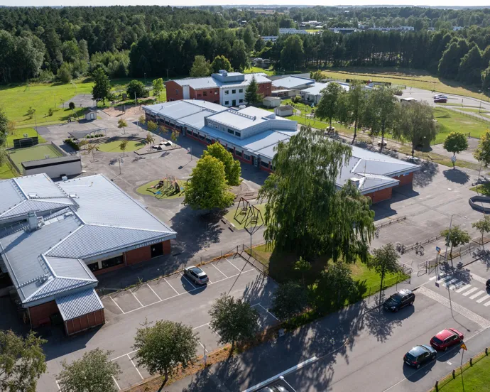 En flygbild av en skolbyggnad med bilar parkerade på den.